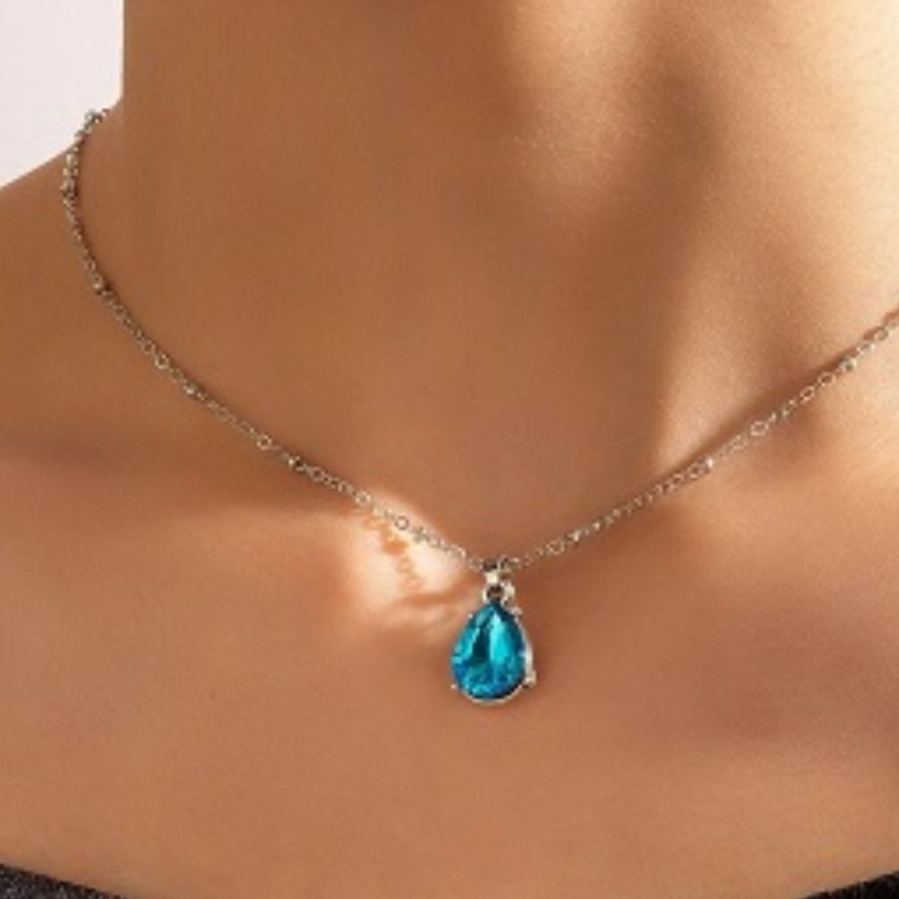 Silver Colored Necklace With Blue Teardrop Pendant